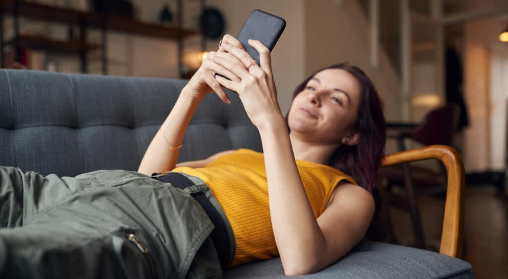 young woman lying on sofa at home looking for her dream horse